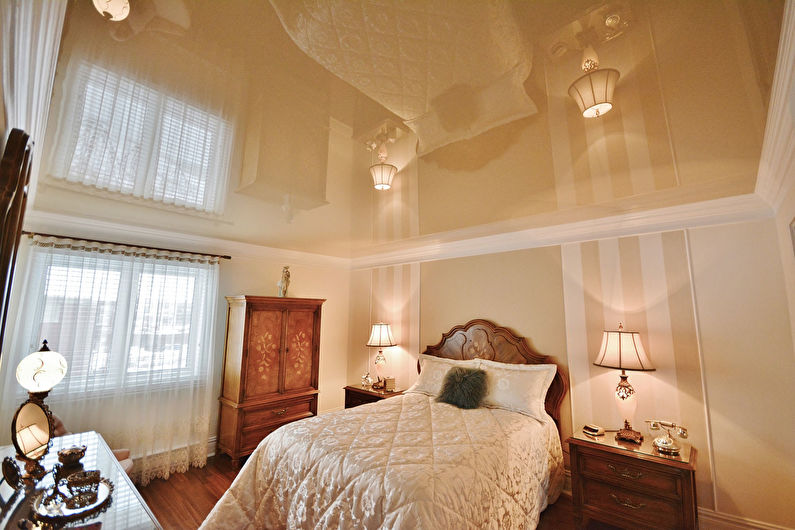 Glossy stretch ceiling in the bedroom interior